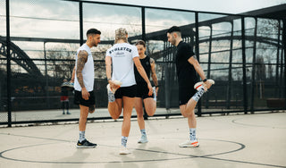 Hybrid Athleten dehnen sich auf einem Basketball Feld und tragen die Hybrid Kollektion.