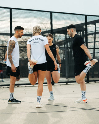 Hybrid Athleten dehnen sich auf einem Basketball Feld und tragen die Hybrid Kollektion.